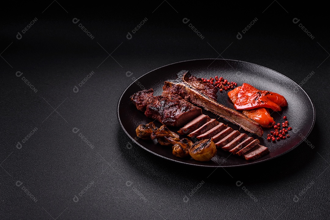 Delicioso bife suculento com sal, especiarias e ervas sobre um fundo escuro de concreto