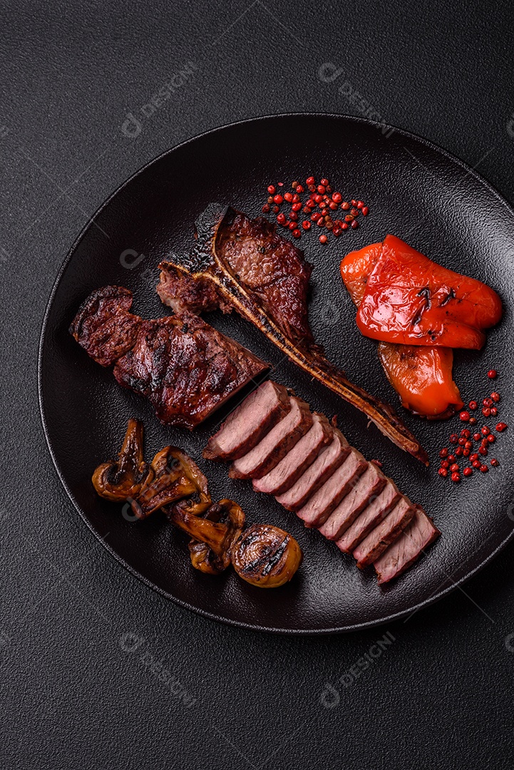 Delicioso bife suculento com sal, especiarias e ervas sobre um fundo escuro de concreto