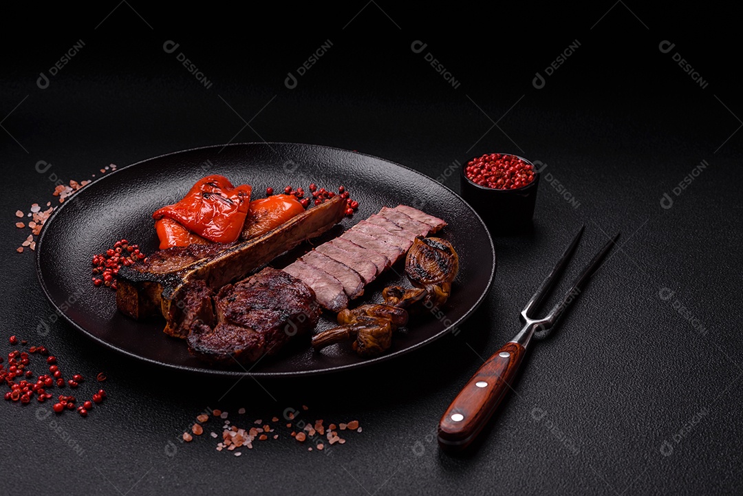 Delicioso bife suculento com sal, especiarias e ervas sobre um fundo escuro de concreto