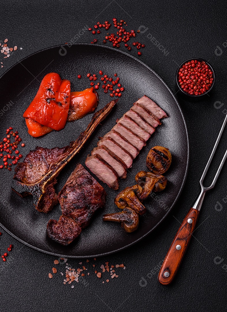 Delicioso bife suculento com sal, especiarias e ervas sobre um fundo escuro de concreto