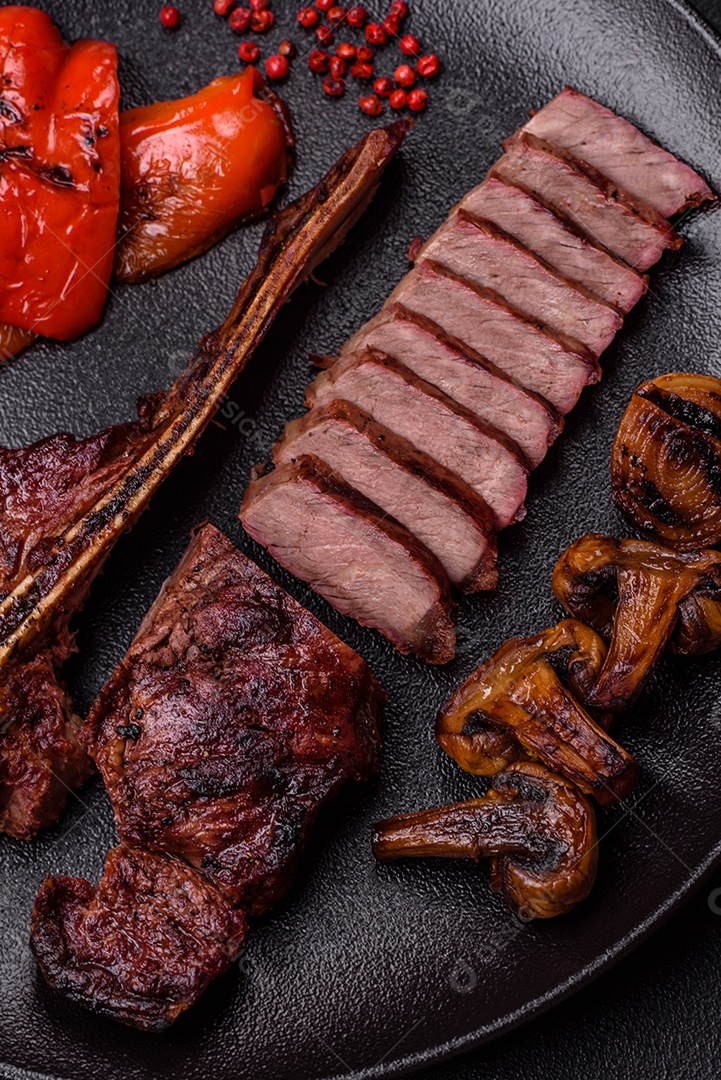 Delicioso bife suculento com sal, especiarias e ervas sobre um fundo escuro de concreto