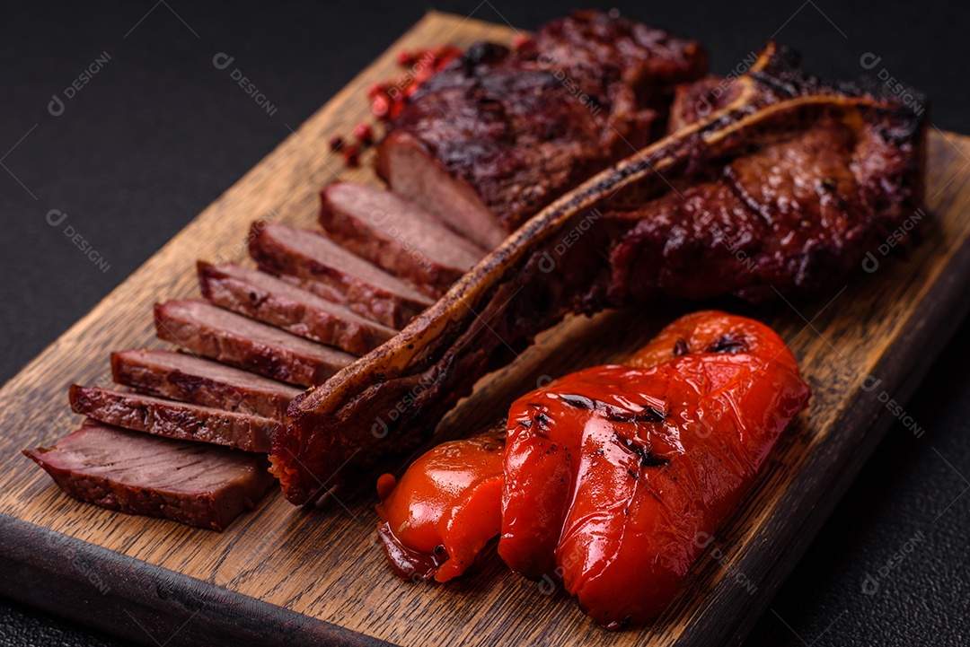Delicioso bife suculento com sal, especiarias e ervas sobre um fundo escuro de concreto