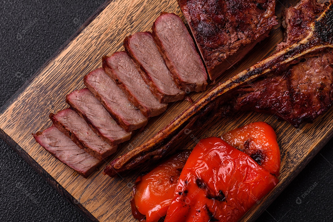 Delicioso bife suculento com sal, especiarias e ervas sobre um fundo escuro de concreto