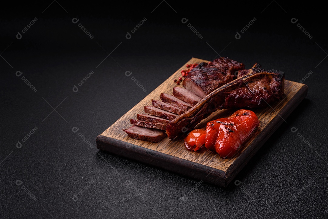 Delicioso bife suculento com sal, especiarias e ervas sobre um fundo escuro de concreto