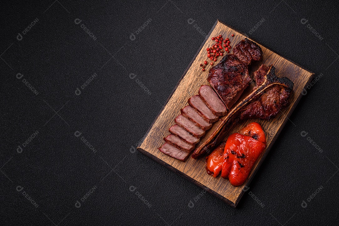 Delicioso bife suculento com sal, especiarias e ervas sobre um fundo escuro de concreto