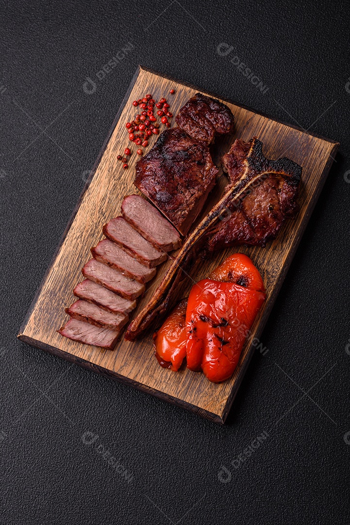 Delicioso bife suculento com sal, especiarias e ervas sobre um fundo escuro de concreto