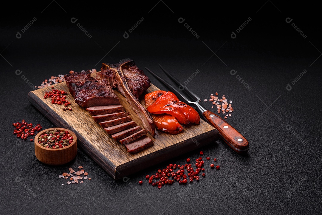 Delicioso bife suculento com sal, especiarias e ervas sobre um fundo escuro de concreto