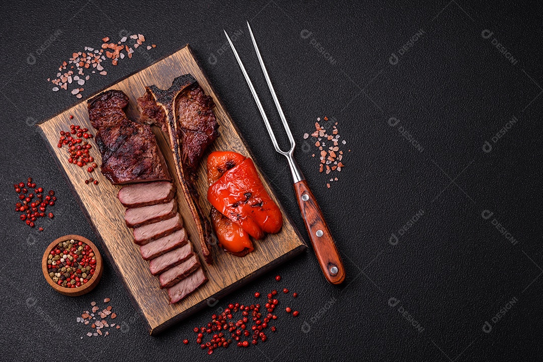 Delicioso bife suculento com sal, especiarias e ervas sobre um fundo escuro de concreto