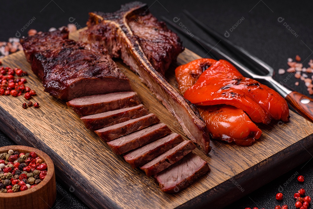 Delicioso bife suculento com sal, especiarias e ervas sobre um fundo escuro de concreto