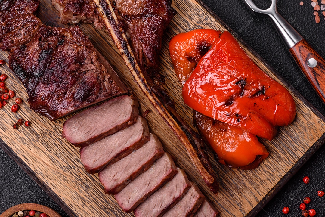 Delicioso bife suculento com sal, especiarias e ervas sobre um fundo escuro de concret