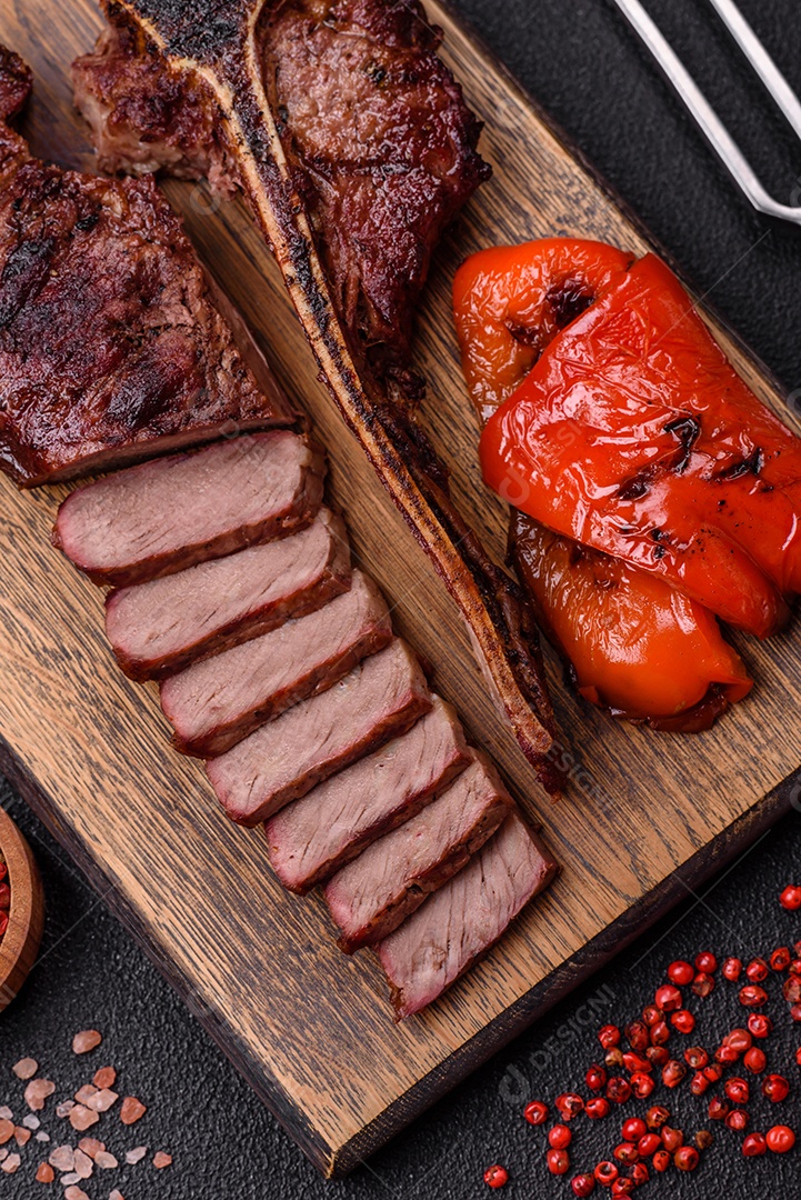 Delicioso bife suculento com sal, especiarias e ervas sobre um fundo escuro de concreto