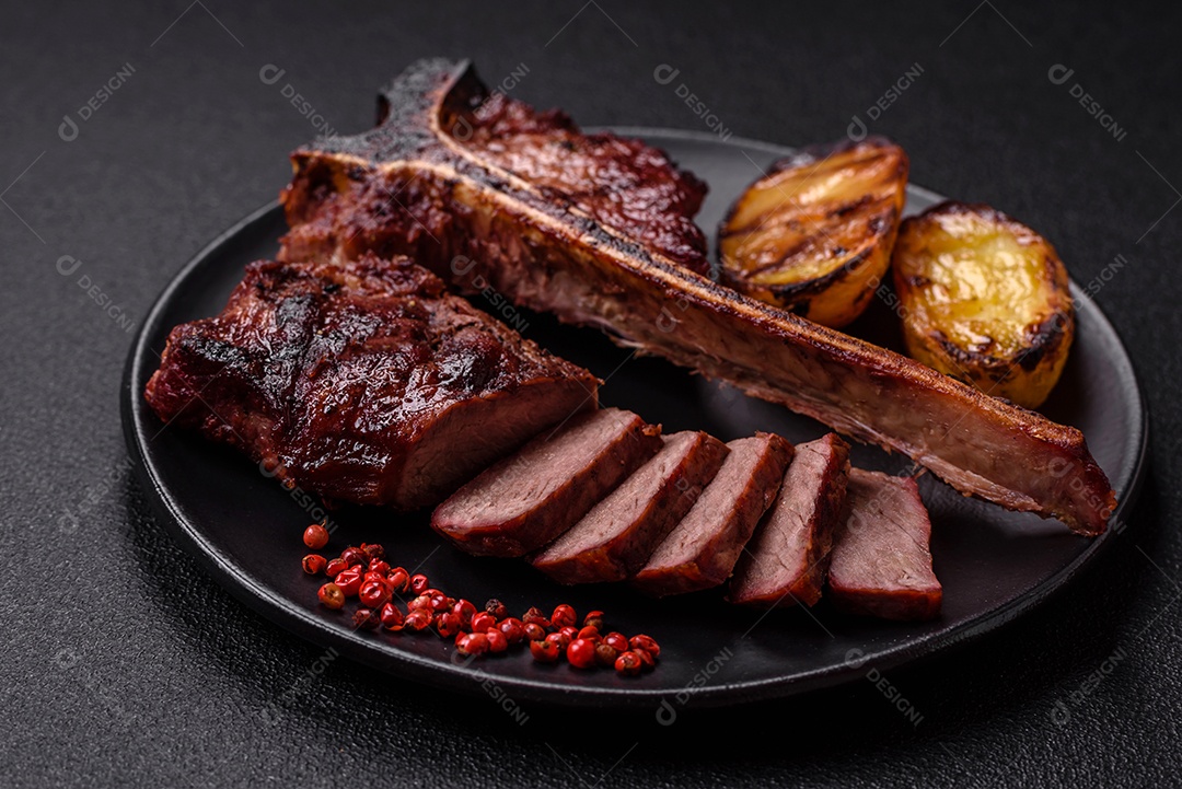 Delicioso bife suculento com sal, especiarias e ervas sobre um fundo escuro de concreto