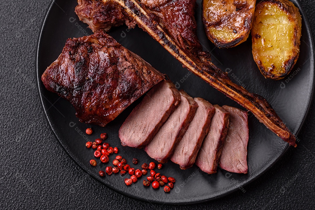Delicioso bife suculento com sal, especiarias e ervas sobre um fundo escuro de concret