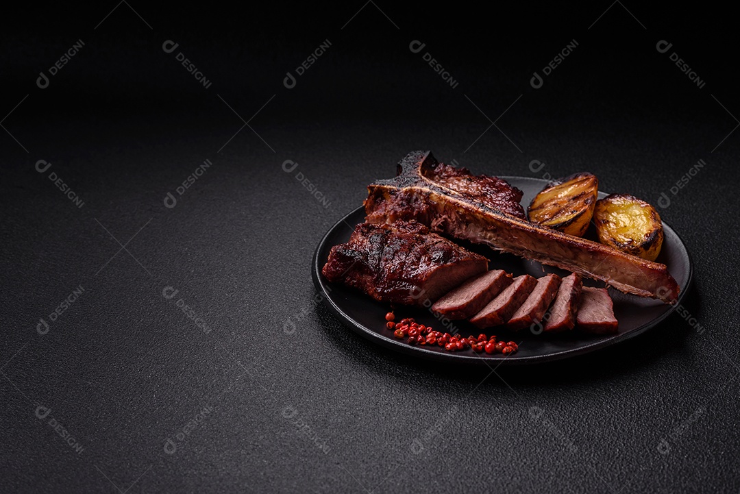 Delicioso bife suculento com sal, especiarias e ervas sobre um fundo escuro de concreto