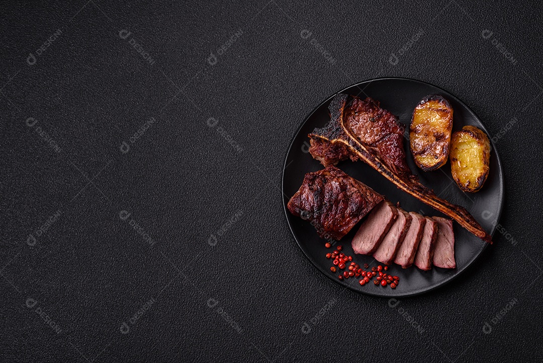 Delicioso bife suculento com sal, especiarias e ervas sobre um fundo escuro de concreto