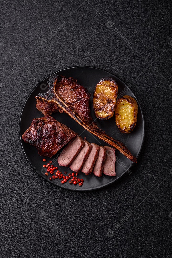 Delicioso bife suculento com sal, especiarias e ervas sobre um fundo escuro de concreto