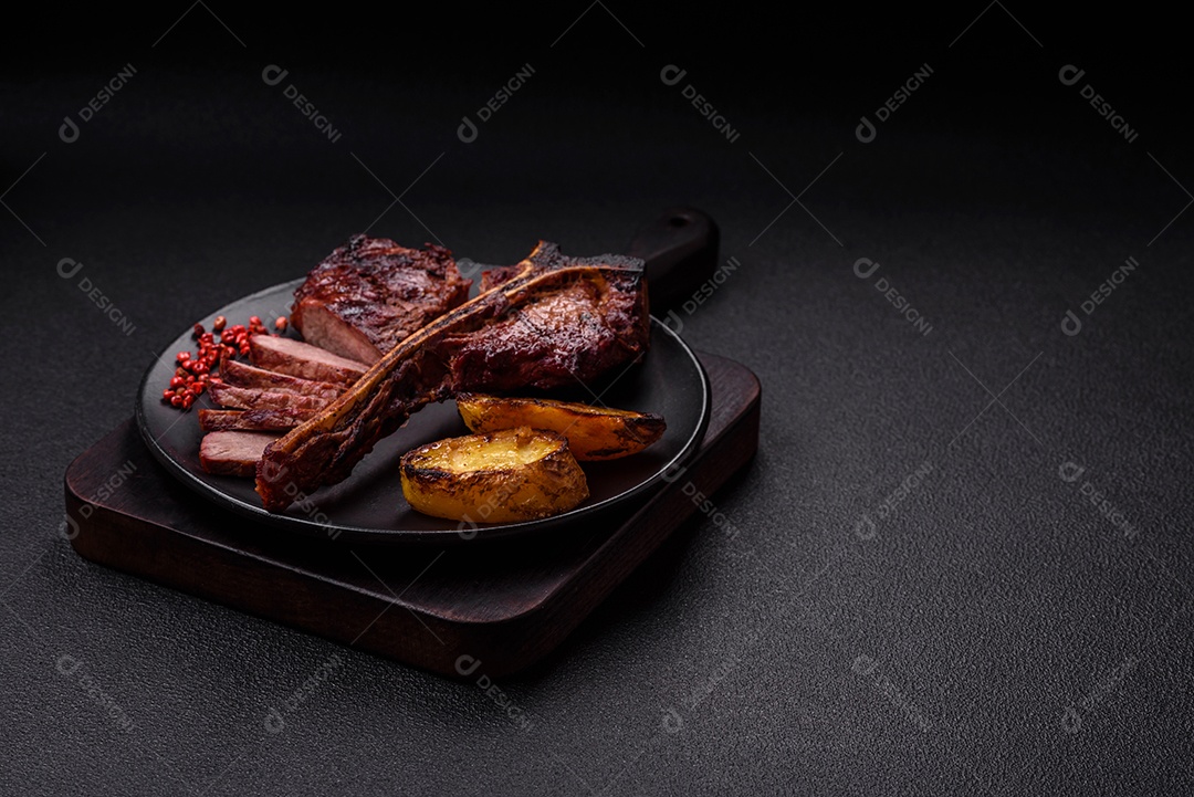 Delicioso bife suculento com sal, especiarias e ervas sobre um fundo escuro de concreto