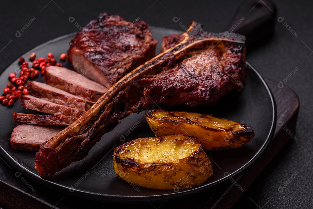 Delicioso bife suculento com sal, especiarias e ervas sobre um fundo escuro de concreto