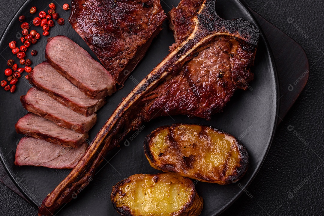 Delicioso bife suculento com sal, especiarias e ervas sobre um fundo escuro de concreto