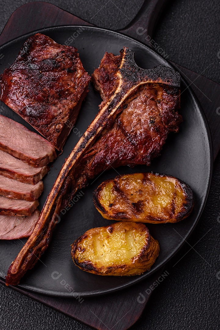 Delicioso bife suculento com sal, especiarias e ervas sobre um fundo escuro de concreto