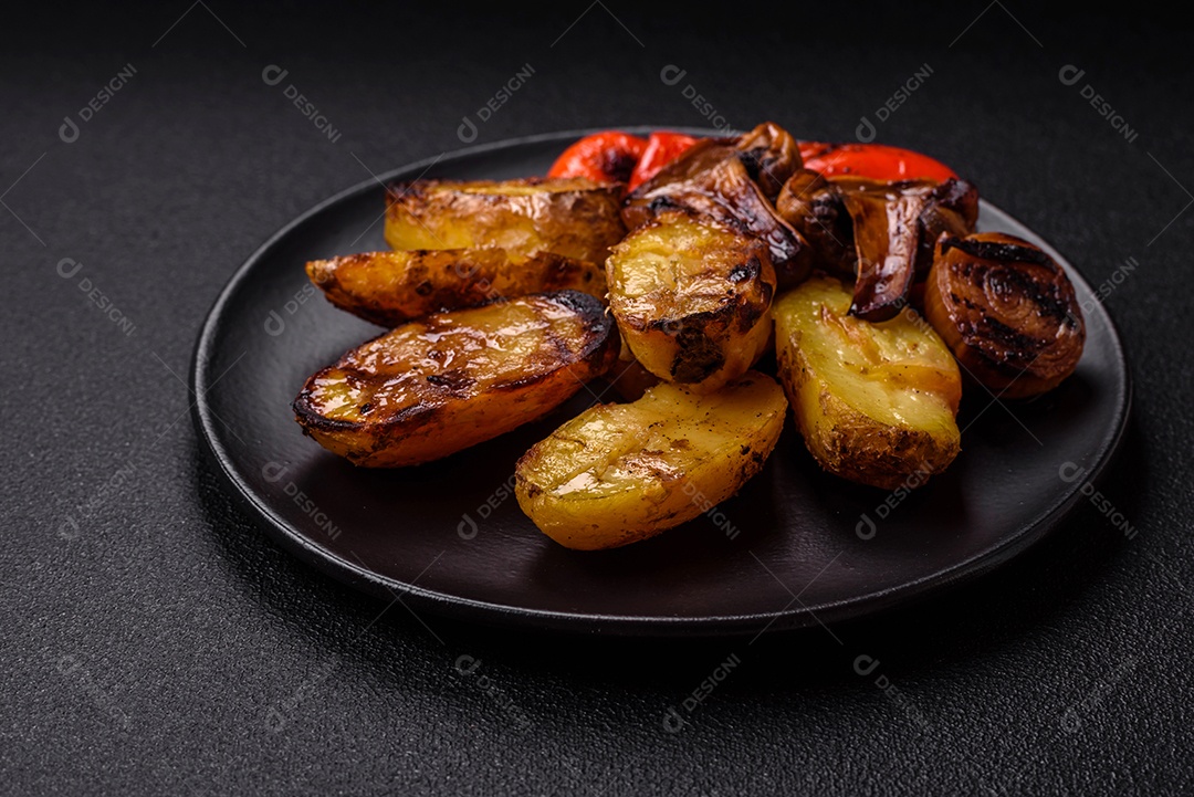 Deliciosos legumes grelhados, batatas, tomates, pimentões, berinjela com sal, especiarias e ervas em um fundo escuro de concreto