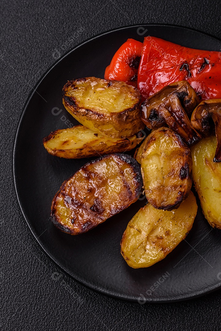 Deliciosos legumes grelhados, batatas, tomates, pimentões, berinjela com sal, especiarias e ervas em um fundo escuro de concreto