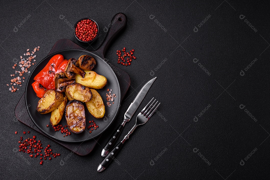 Deliciosos legumes grelhados, batatas, tomates, pimentões, berinjela com sal, especiarias e ervas em um fundo escuro de concreto