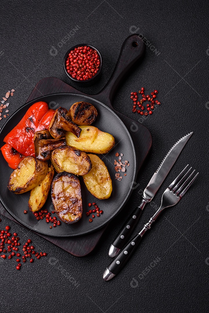 Deliciosos legumes grelhados, batatas, tomates, pimentões, berinjela com sal, especiarias e ervas em um fundo escuro de concreto