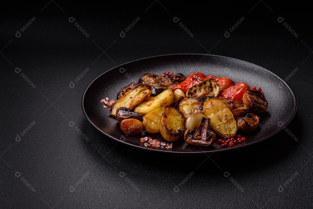 Deliciosos legumes grelhados, batatas, tomates, pimentões, berinjela com sal, especiarias e ervas em um fundo escuro de concreto