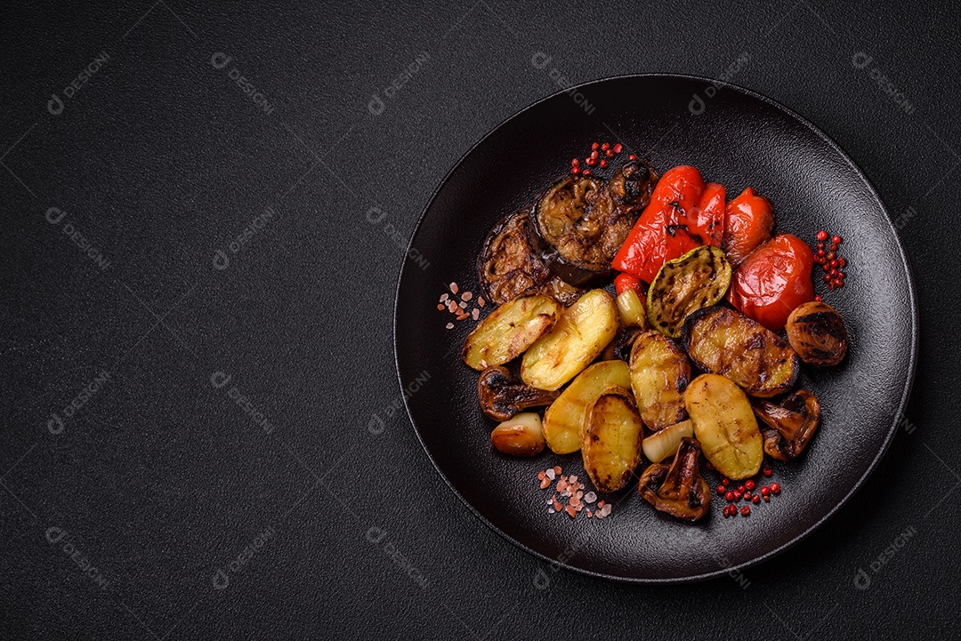 Deliciosos legumes grelhados, batatas, tomates, pimentões, berinjela com sal, especiarias e ervas em um fundo escuro de concreto