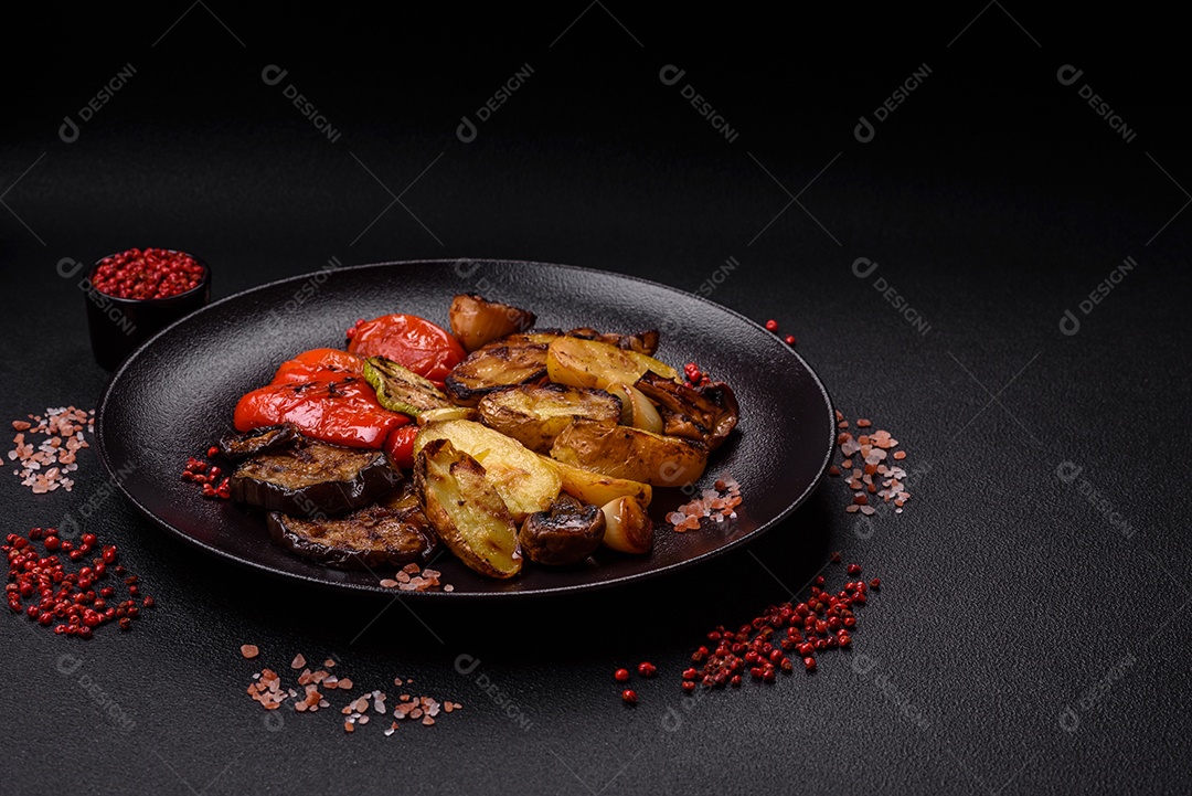Deliciosos legumes grelhados, batatas, tomates, pimentões, berinjela com sal, especiarias e ervas em um fundo escuro de concreto