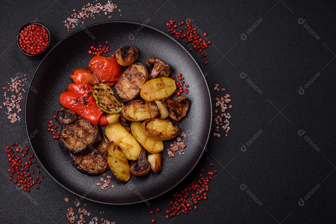 Deliciosos legumes grelhados, batatas, tomates, pimentões, berinjela com sal, especiarias e ervas em um fundo escuro de concreto