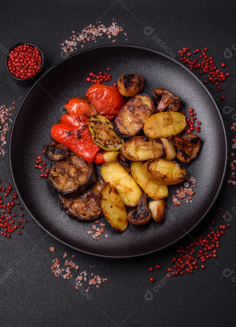 Deliciosos legumes grelhados, batatas, tomates, pimentões, berinjela com sal, especiarias e ervas em um fundo escuro de concret