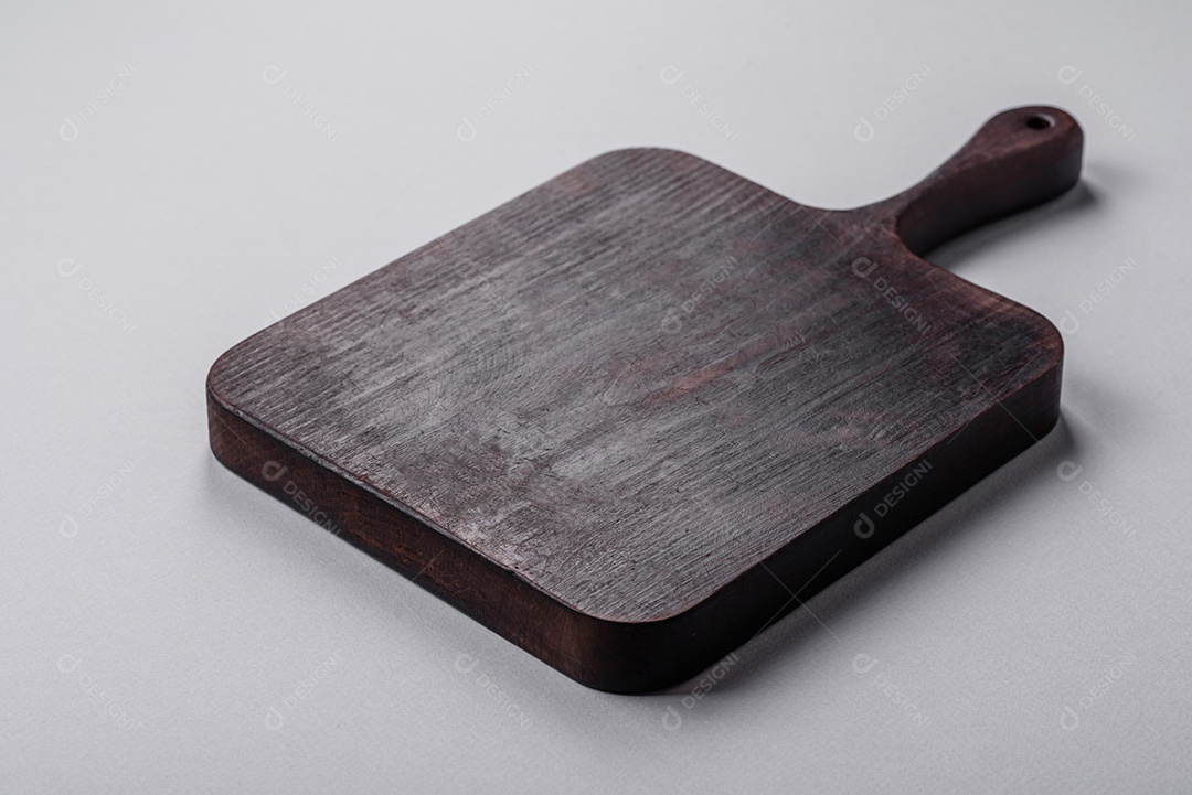 Tábua de corte de madeira vazia em fundo de concreto texturizado cinza. Talheres, preparação para o jantar