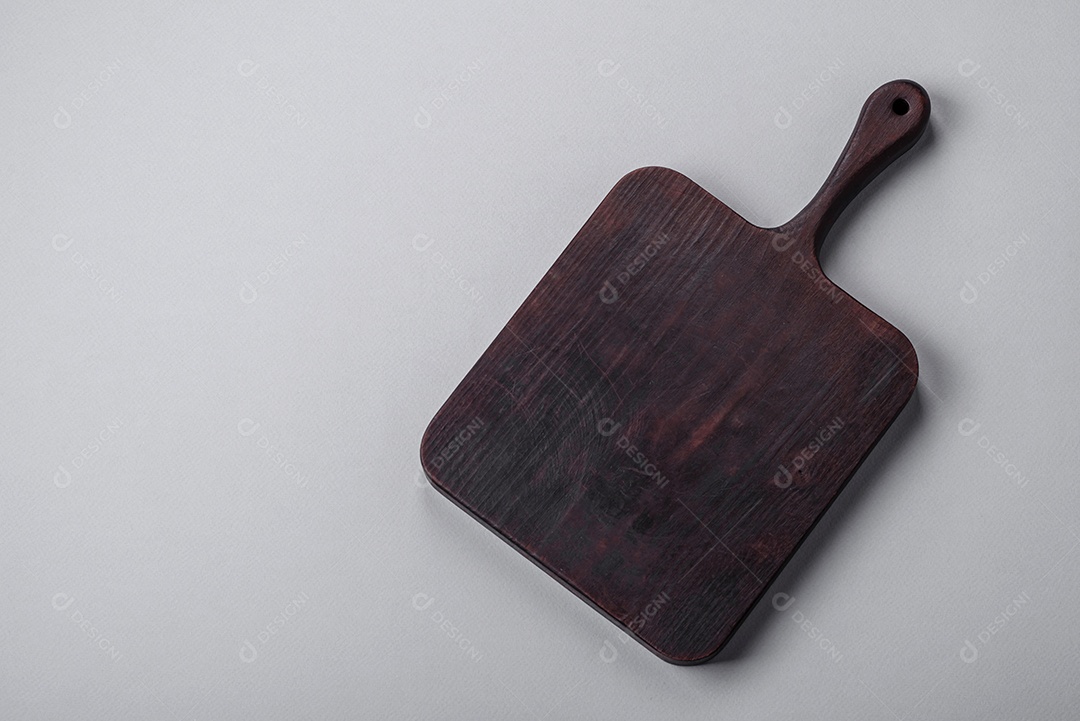 Tábua de corte de madeira vazia em fundo de concreto texturizado cinza. Talheres, preparação para o jantar