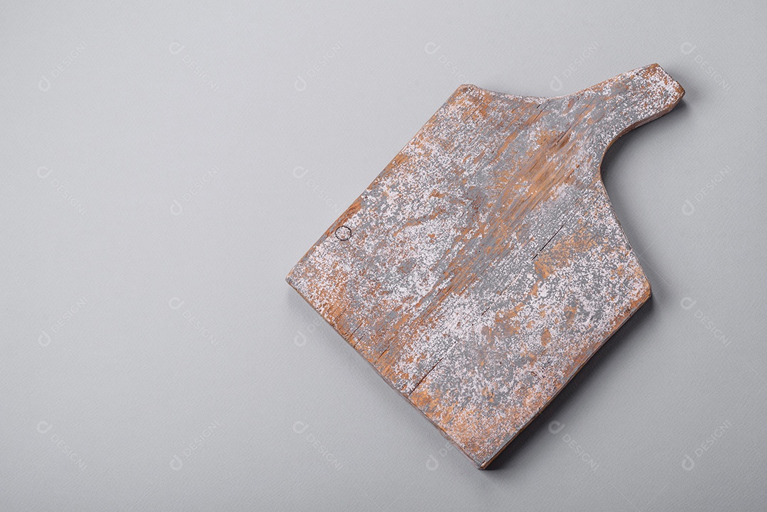 Tábua de corte de madeira vazia em fundo de concreto texturizado cinza. Talheres, preparação para o jantar