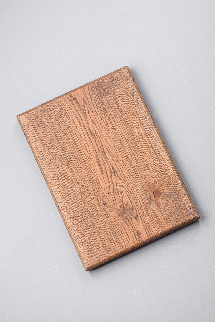 Tábua de corte de madeira vazia em fundo de concreto texturizado cinza. Talheres, preparação para o jantar