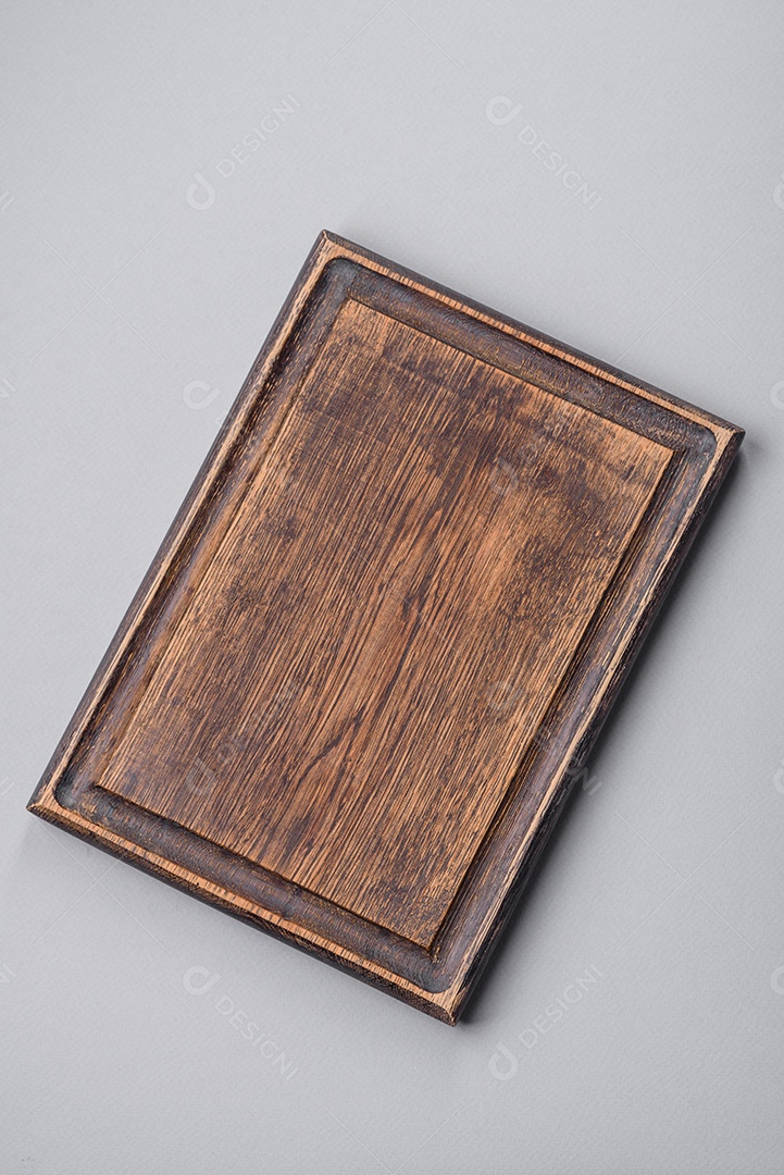 Tábua de corte de madeira vazia em fundo de concreto texturizado cinza. Talheres, preparação para o jantar