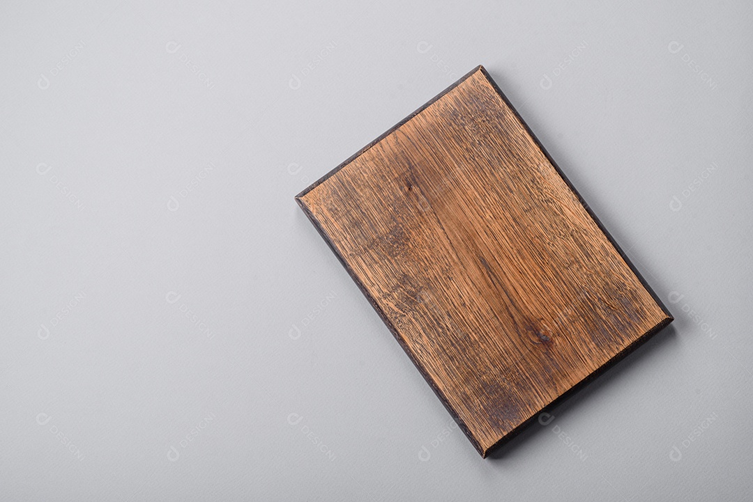 Tábua de corte de madeira vazia em fundo de concreto texturizado cinza. Talheres, preparação para o jantar