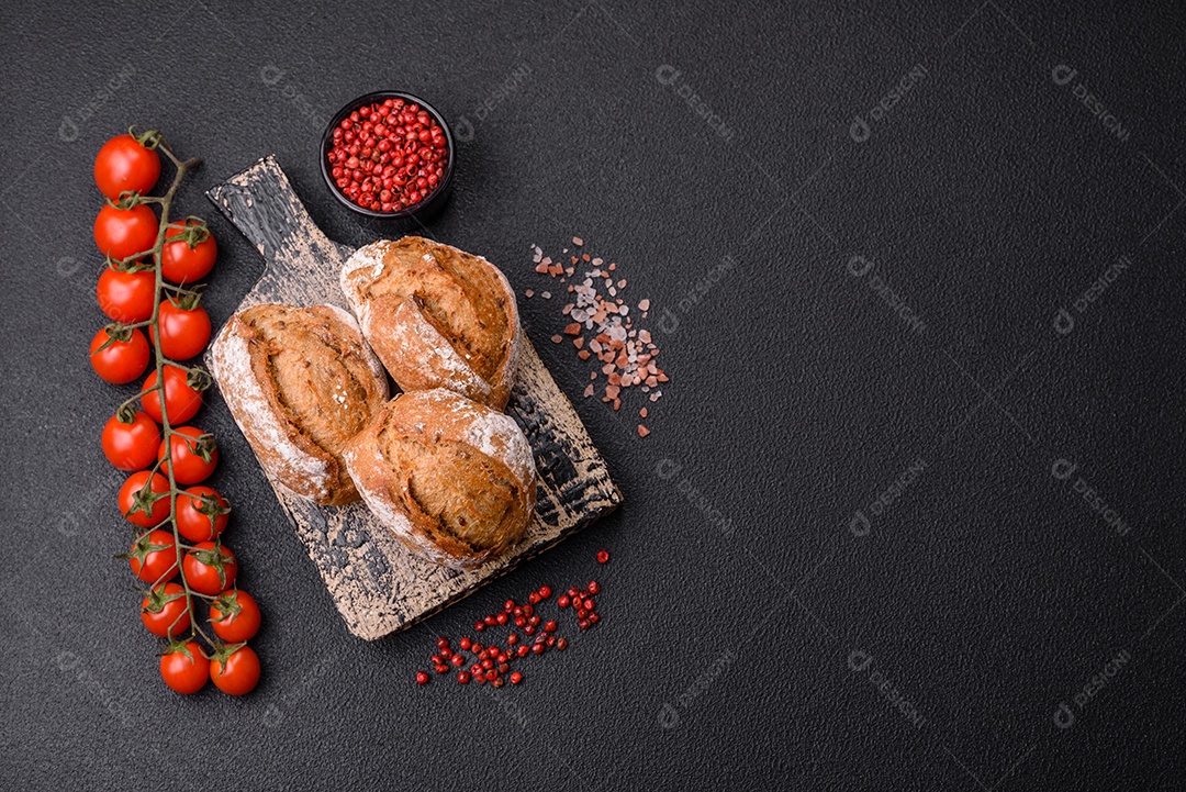 Pãezinhos de pão fresco com sal, especiarias, sementes e grãos sobre fundo escuro