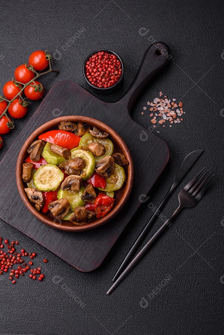 Deliciosos legumes grelhados, batatas, tomates, pimentões, berinjela com sal, especiarias e ervas em um fundo escuro de concreto