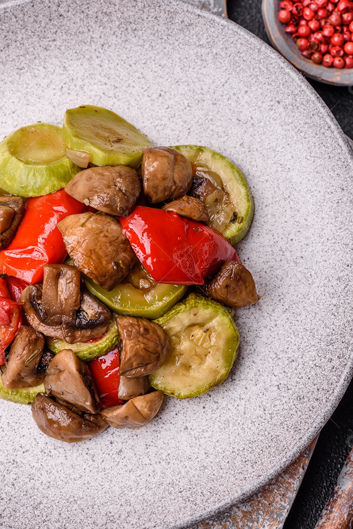 Deliciosos legumes grelhados, batatas, tomates, pimentões, berinjela com sal, especiarias e ervas em um fundo escuro de concreto