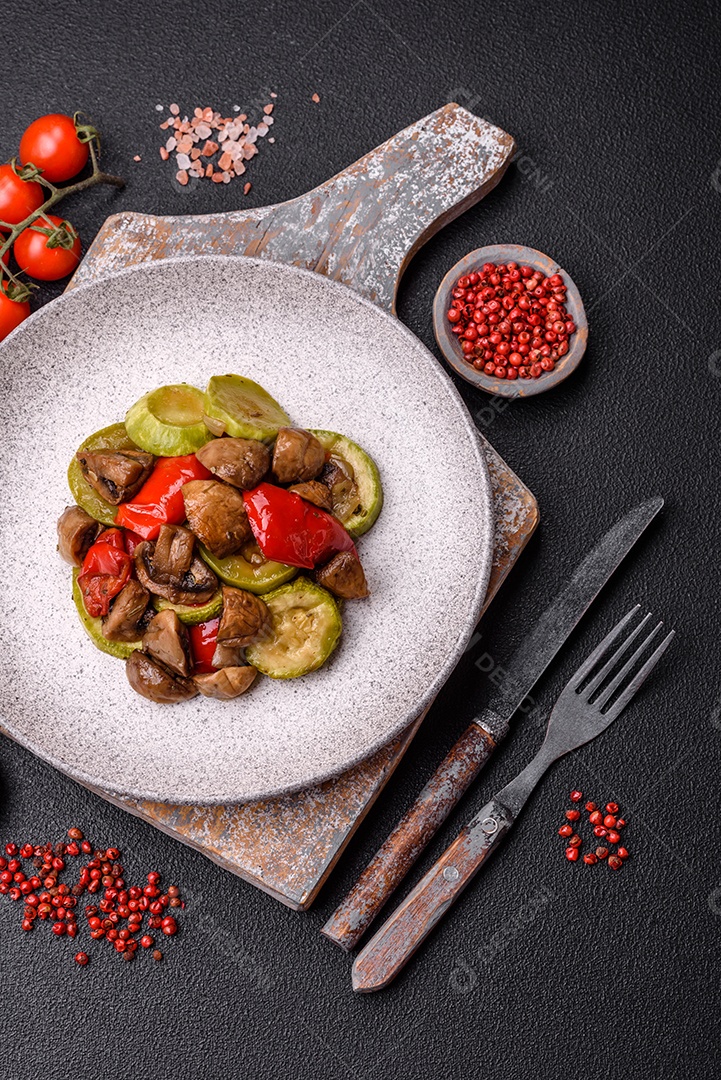 Deliciosos legumes grelhados, batatas, tomates, pimentões, berinjela com sal, especiarias e ervas em um fundo escuro de concreto