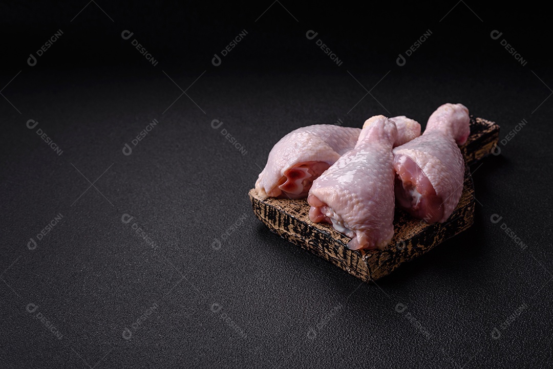 Coxas de frango cru fresco com sal e especiarias em fundo escuro de concreto
