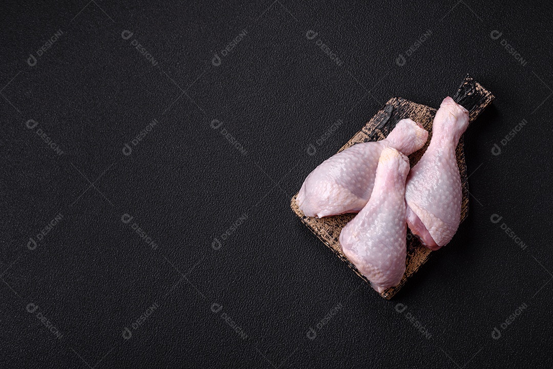 Coxas de frango cru fresco com sal e especiarias em fundo escuro de concreto
