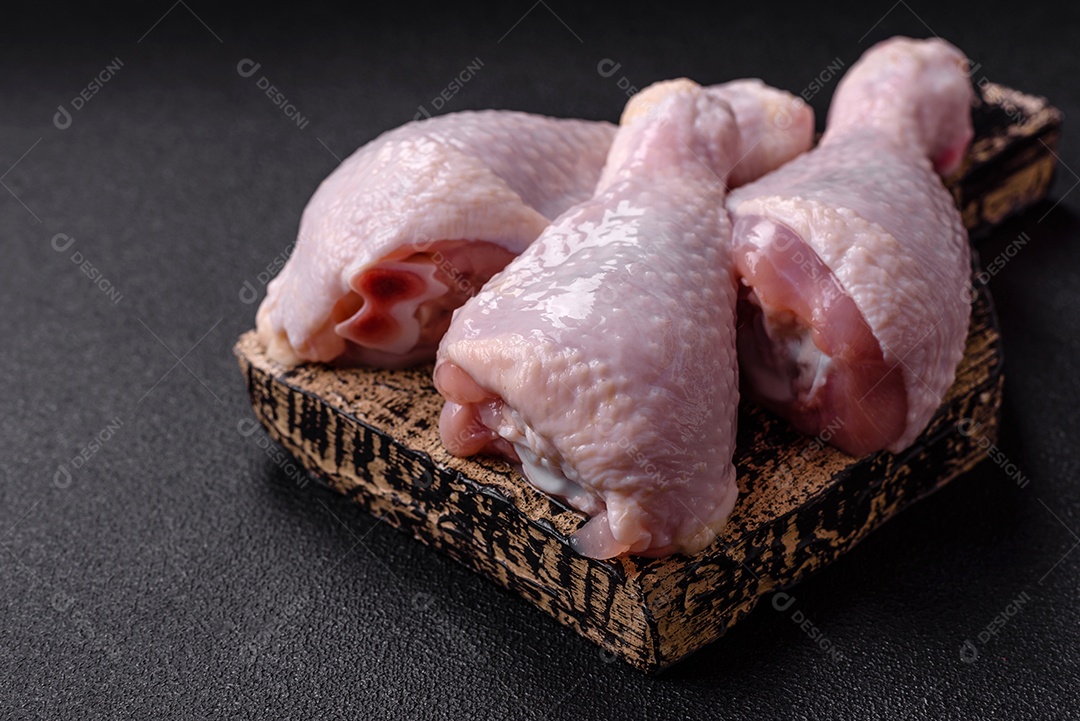 Coxas de frango cru fresco com sal e especiarias em fundo escuro de concreto