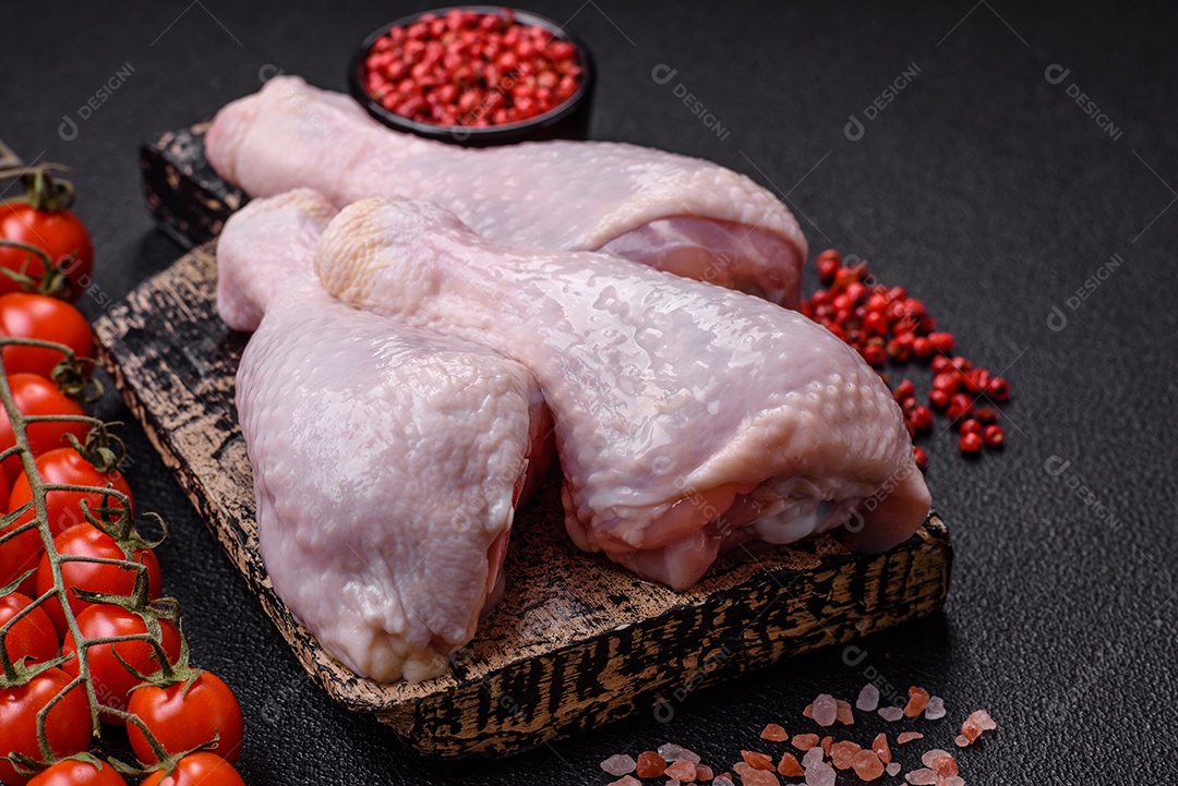 Coxas de frango cru fresco com sal e especiarias em fundo escuro de concreto
