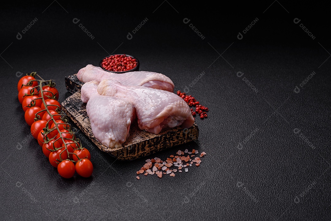Coxas de frango cru fresco com sal e especiarias em fundo escuro de concreto