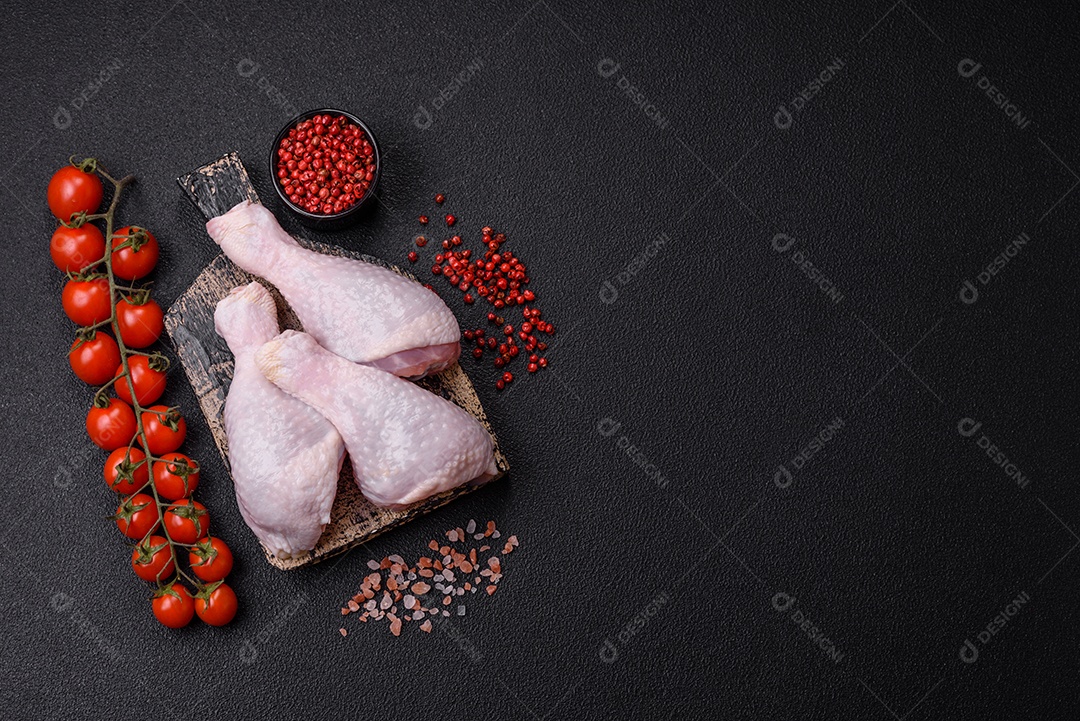 Coxas de frango cru fresco com sal e especiarias em fundo escuro de concreto