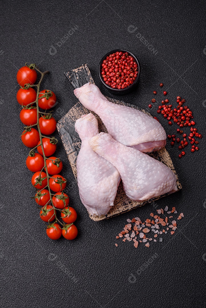 Coxas de frango cru fresco com sal e especiarias em fundo escuro de concreto